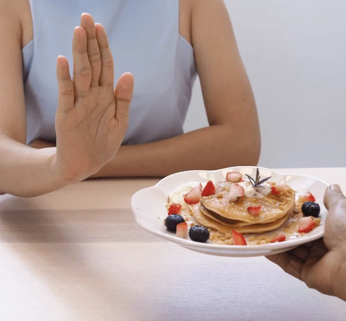 Woman declining a plate of pancakes, illustrating the craving control Alkatide is formulated to support